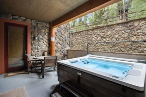 Ein Wellnessbereich mit Whirlpool, Steinwänden und einer Holztür.