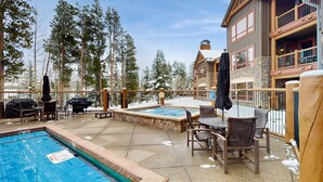 A pool area with a hot tub, outdoor seating, and a view of a lodge building. - Penthouse Ski-in/Ski-out: hot tubs, heated pool, gym, ski storage, shuttle (Breckenridge)