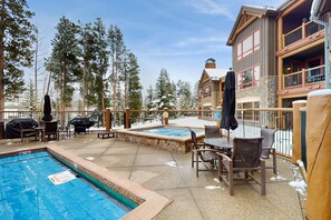 Uma área de piscina com hidromassagem, área de estar ao ar livre e vista para um edifício de pousada.