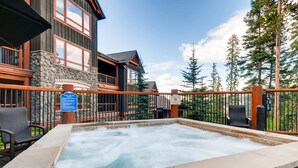 A hot tub area with a stone wall, wooden deck, and a sign indicating a pool and spa. - Penthouse Ski-in/Ski-out: hot tubs, heated pool, gym, ski storage, shuttle (Breckenridge)