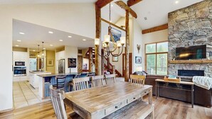 Une cuisine spacieuse avec un grand îlot central, une table à manger en bois et une cheminée en pierre.