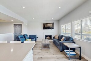 A modern living room with a fireplace, a sofa, a coffee table, and a dining area. - Updated townhome in gated community  w/ shared pool & jacuzzi - walk to beach (Port Hueneme)