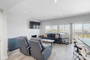 A modern living room with a sofa, chairs, a coffee table, and a TV. - Updated townhome in gated community  w/ shared pool & jacuzzi - walk to beach (Port Hueneme)