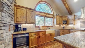 Una cocina con armarios de madera, una pared de piedra y un ventanal grande.