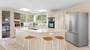 A modern kitchen with a central island, bar stools, a refrigerator, and a microwave.