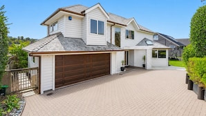 A two-story house with a garage, a covered porch, and a landscaped driveway.