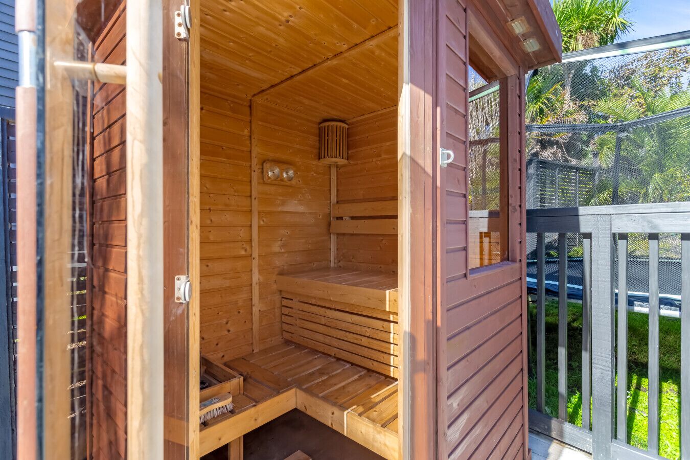 A wooden sauna with a bench, a window, and a door.