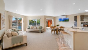 A spacious living area with a sofa, a dining table, and a kitchen area with a bar.