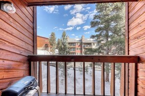 A wooden cabin with a balcony, a grill, and a view of a building and trees. - In-town condo with ideal walk-to-lifts location, pool, hot tubs & sauna (Breckenridge)