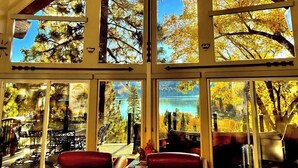 A room with large windows, a fireplace, and a view of trees and a lake. - Incredible Lake View, Private Hot Tub, Huge Game Room, A/C,-Short Walk to Lake (Lake Arrowhead)