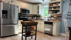 Una cocina con electrodomésticos de acero inoxidable, una mesa de madera y un lavavajillas.