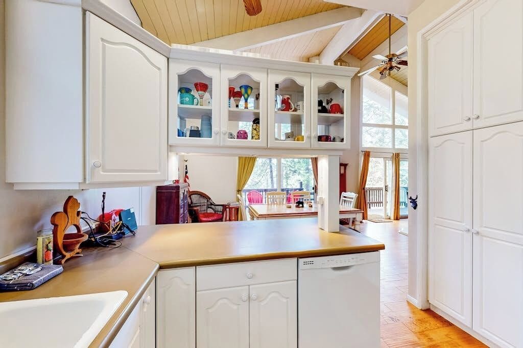 A kitchen with white cabinetry, a wooden countertop, and a view to an outdoor dining area.