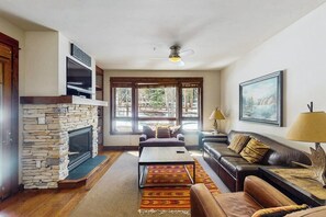 Ein Wohnzimmer mit Kamin aus Stein, einer Couch, einem Couchtisch und einem Gemälde an der Wand.