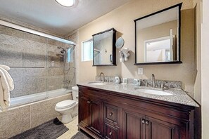 A bathroom with a shower, two sinks, a toilet, and a large mirror. - Dog-friendly rural home with deck, wood fireplace, fast WiFi, patio & gas grill (Crestline)
