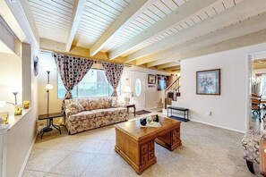 A living room with a sofa, coffee table, and a staircase leading to another level. - Dog-friendly rural home with deck, wood fireplace, fast WiFi, patio & gas grill (Crestline)