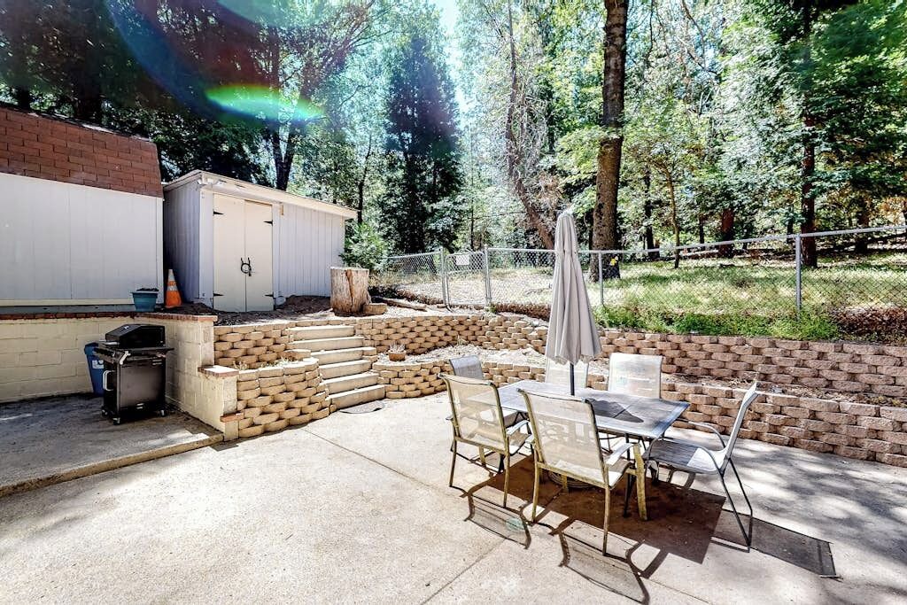 A patio with a table and chairs, a grill, and a shed.