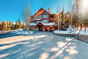 A lodge with a central entrance, multiple floors, and a snow-covered landscape. - Luxury ski-in/out condo with outdoor pool, hot tubs, gym & game room (Breckenridge)