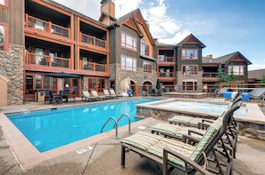 A hotel with a pool, outdoor seating, and a stone facade. - Luxury ski-in/out condo with outdoor pool, hot tubs, gym & game room (Breckenridge)