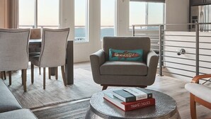 Un salon moderne avec un canapé, un fauteuil, une table à manger et des livres posés sur une table basse.
