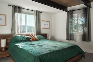 Ein Schlafzimmer mit einem Bett, zwei Vorhängen und gerahmten Bildern an den Wänden.