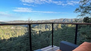 Un balcon doté de meubles en osier et offrant une vue sur un paysage montagneux.