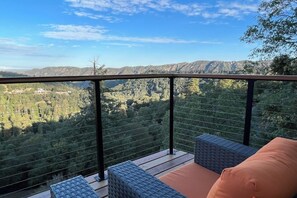 Ein Balkon mit Korbmöbeln und Blick auf eine gebirgige Landschaft.