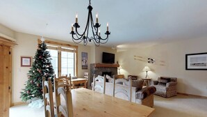 Ein Essbereich mit Holztisch und -stühlen, einem Weihnachtsbaum, einem Kamin und einem Fernseher an der Wand.