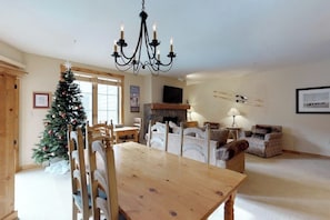 Ein Essbereich mit Holztisch und -stühlen, einem Weihnachtsbaum, einem Kamin und einem Fernseher an der Wand.
