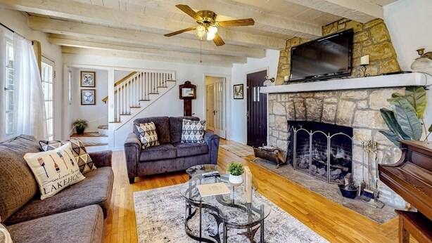 A living room with a fireplace, a television mounted above it, and a ceiling fan.