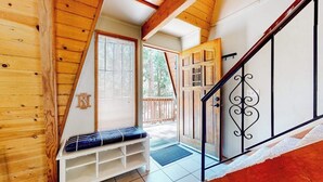 A wooden interior with a bench, a staircase, and a door leading outside. - Dog-friendly 2-story home with large deck, tree views, fireplace, & W/D (Crestline)