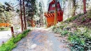 A rustic cabin with a balcony, surrounded by dense forest and a gravel path. - Dog-friendly 2-story home with large deck, tree views, fireplace, & W/D (Crestline)