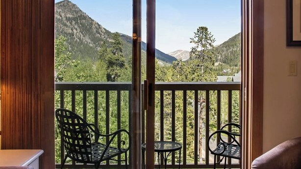 A room with a sliding glass door leading to a balcony with a mountain view. - Walk to the Slopes from this Condo with Great Views, Shared Pool, Hot Tub & Sauna (Keystone)