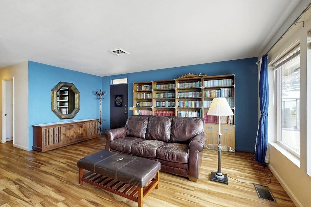 Een woonkamer met een leren bank, een houten bankje en een boekenkast.
