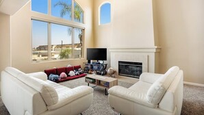 A living room with a fireplace, a TV, and a sofa set. - Oceanview home with rooftop deck and game room - dog-friendly (Oxnard)