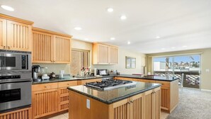 A modern kitchen with wooden cabinets, stainless steel appliances, and a large island. - Oceanview home with rooftop deck and game room - dog-friendly (Oxnard)