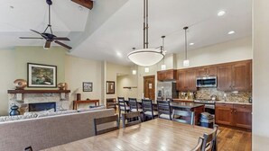 A spacious kitchen with wooden cabinets, a dining area with a large wooden table, and a ceiling fan. - Spacious, walk-to-lift condo with vaulted ceilings, pool, hot tubs & gym (Breckenridge)
