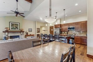 Une cuisine spacieuse avec des meubles en bois, un coin repas doté d’une grande table en bois et un ventilateur de plafond.