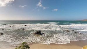 Una playa con olas, rocas y cielo despejado.