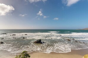 Ein Strand mit Wellen, Felsen und blauem Himmel.