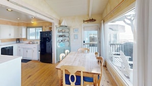 Una cocina con armarios de madera, un refrigerador negro y una mesa de comedor con sillas.