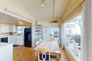 Eine Küche mit Holzausstattung, einem schwarzen Kühlschrank und einem Esstisch mit Stühlen.