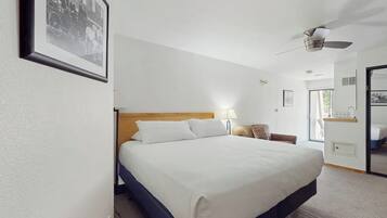 A hotel room with a bed, a ceiling fan, a bedside table, and a framed picture on the wall.