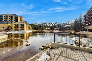 Ein Hotel mit Blick auf ein Gebirge, ein Gewässer und eine Fußgängerbrücke.
