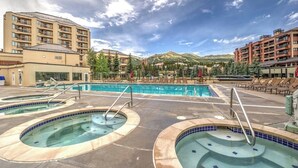 Et hotel med poolområde, flere boblebade og udsigt til et bjerg.