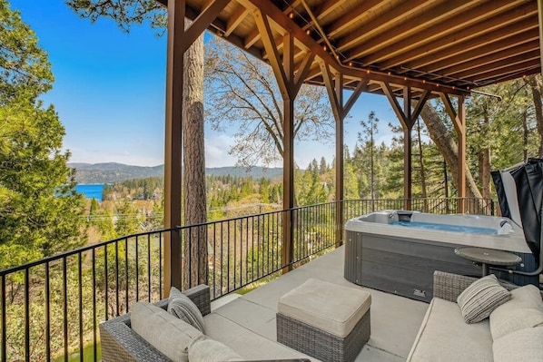 Ein überdachter Außenbereich mit Whirlpool, mit Blick auf eine bewaldete Landschaft.
