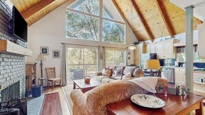 Un amplio salón con chimenea, ventanas grandes y una acogedora disposición de asientos.