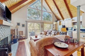 Un vaste espace de vie agrémenté d’une cheminée, de grandes fenêtres et d’un coin salon confortable.