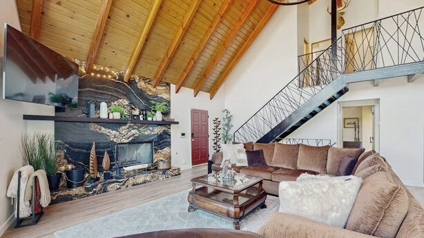 Un amplio salón con chimenea, un sofá, una mesa de centro y una escalera.