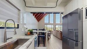 Una cocina moderna con una isla grande, un refrigerador empotrado y un comedor con vistas.
