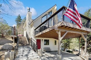 A two-story house with a balcony, a red door, and an American flag. - Modern chalet w/expansive deck, gas grill, & game room - close to lake & town (Lake Arrowhead)